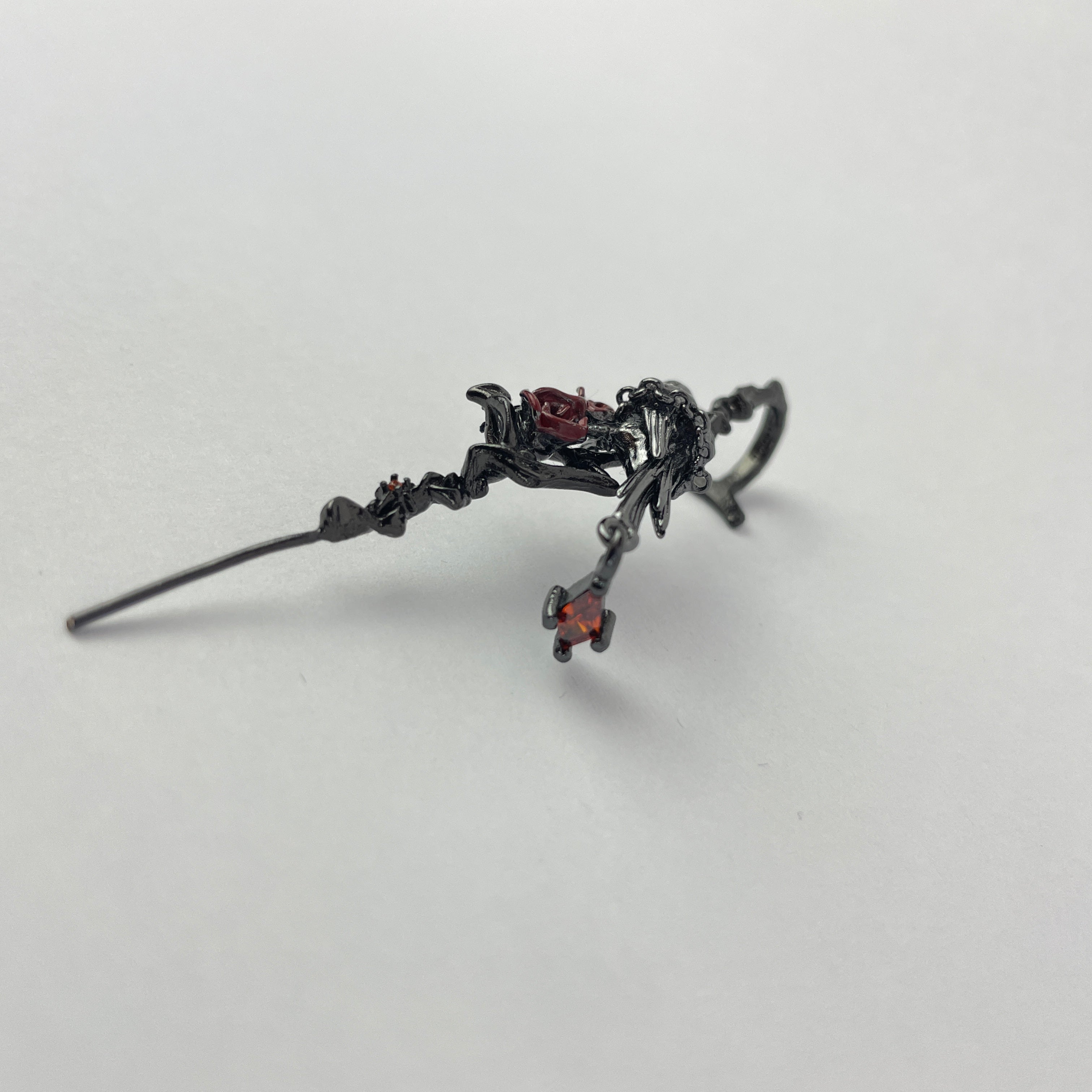 Black earring with decorative elements on a light gray background