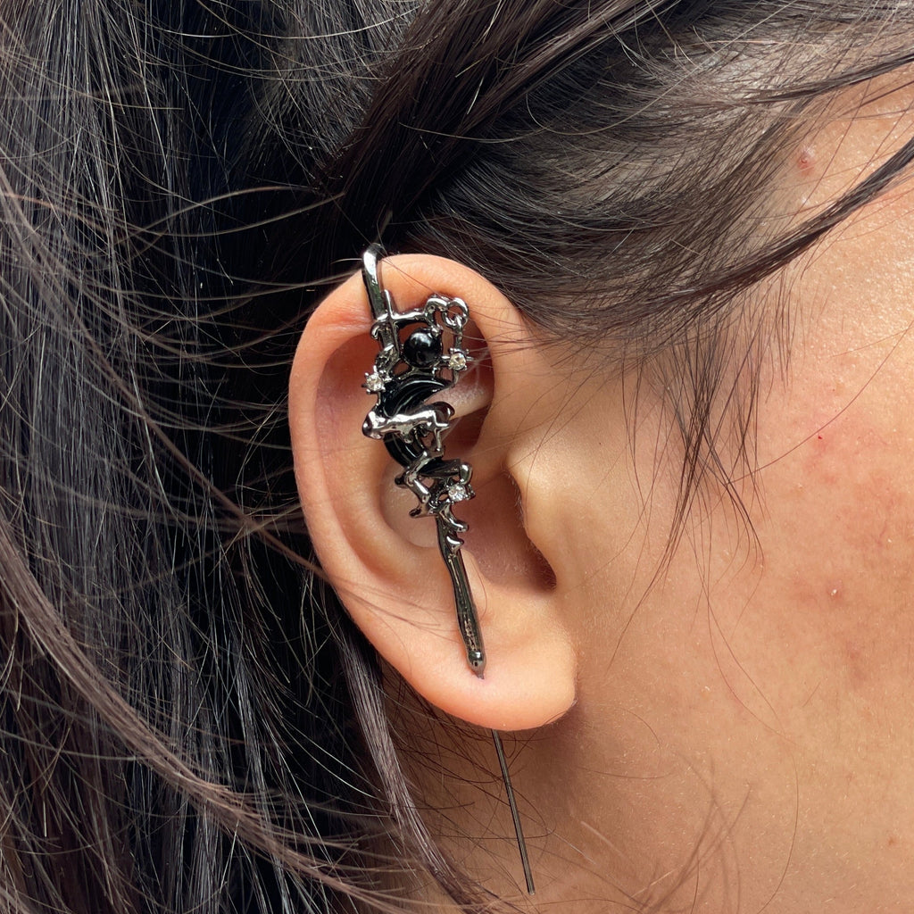 Close-up of an ear with a decorative earring and hair tied back.