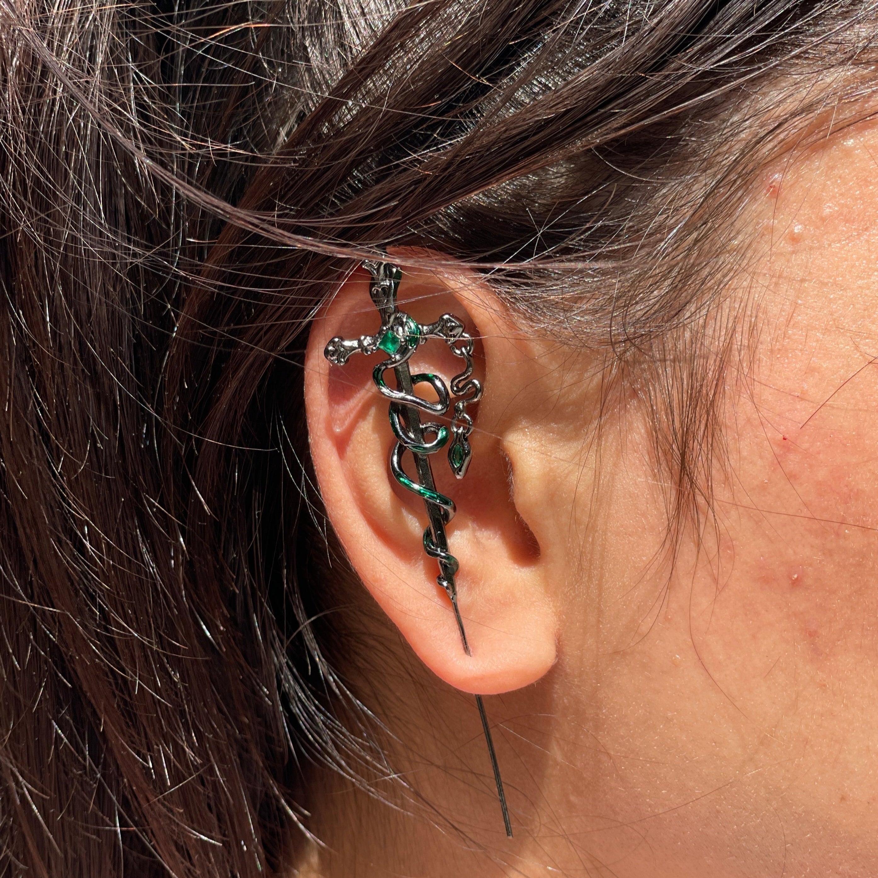 Close-up of an ear with a decorative earring and hair details.