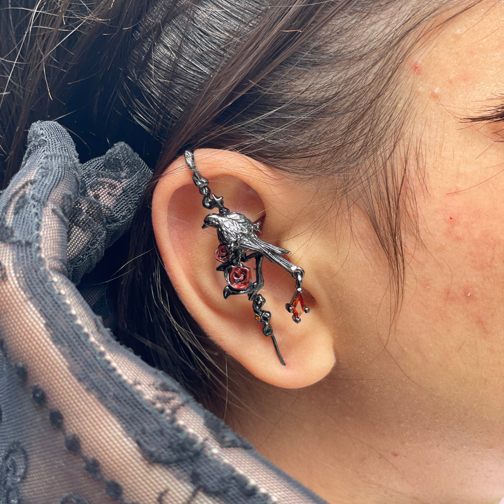 Close-up of an ear with a decorative earring, wearing a patterned garment.
