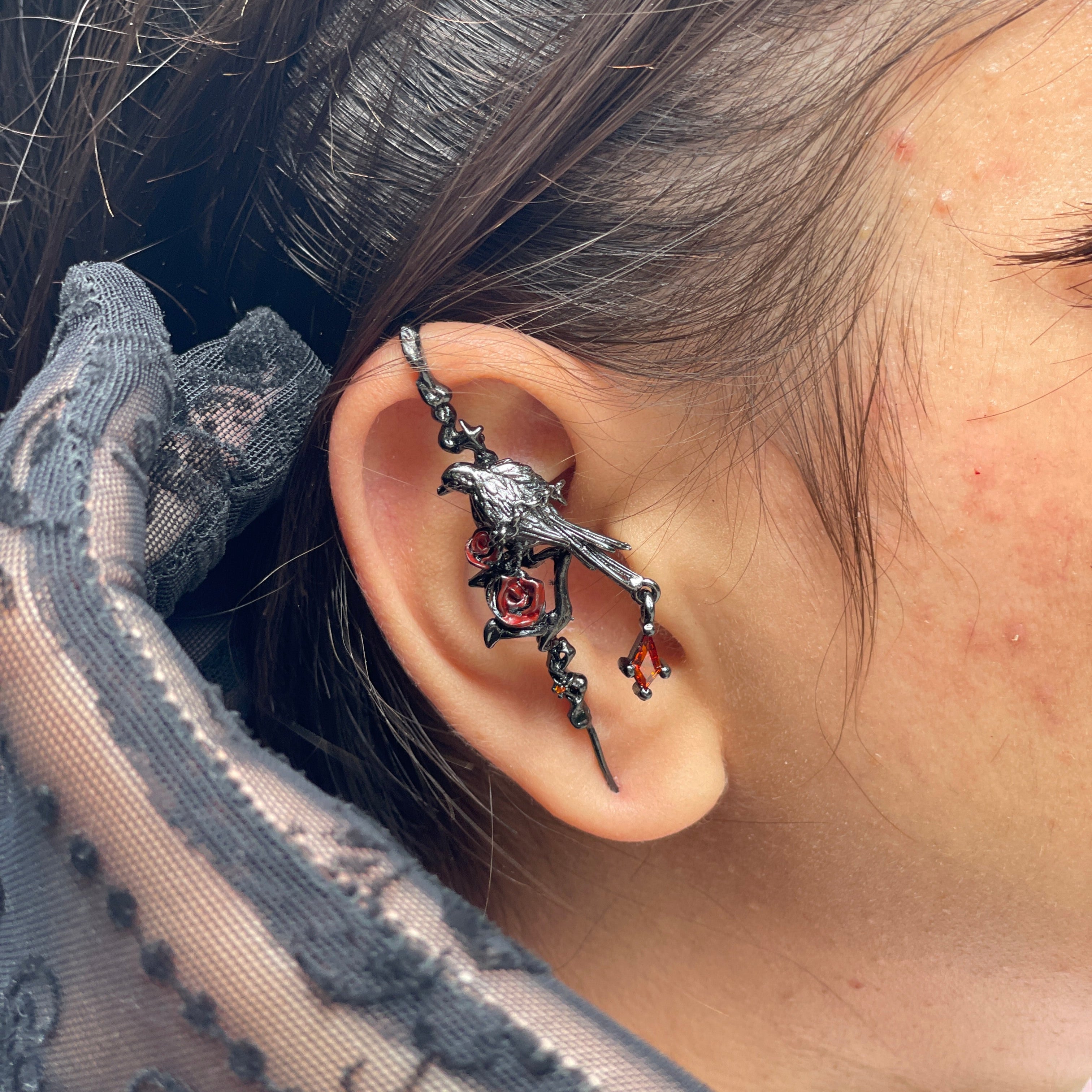 Close-up of an ear with a decorative earring, wearing a patterned garment.