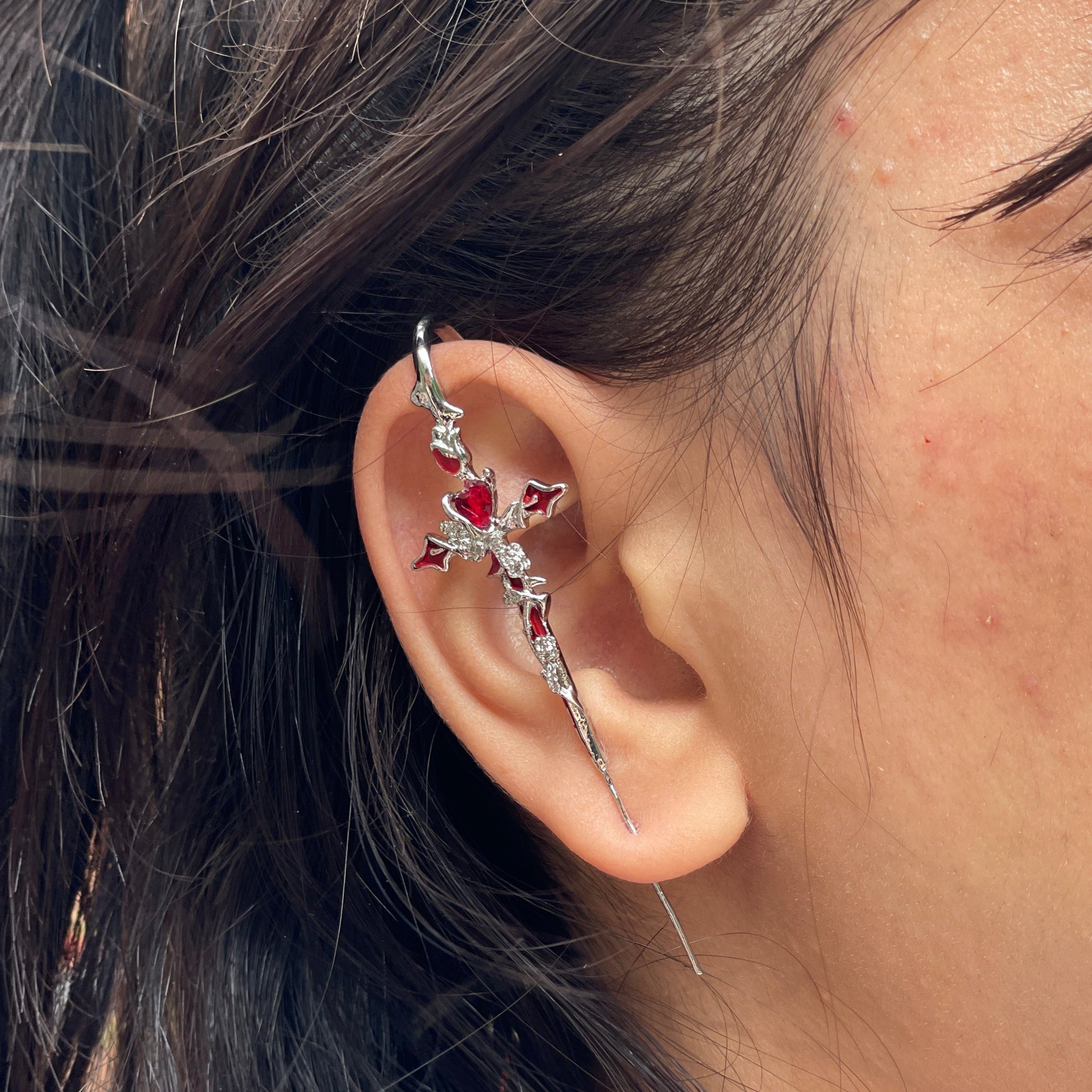 Close-up of an ear with a decorative earring, hair partially covering the face.