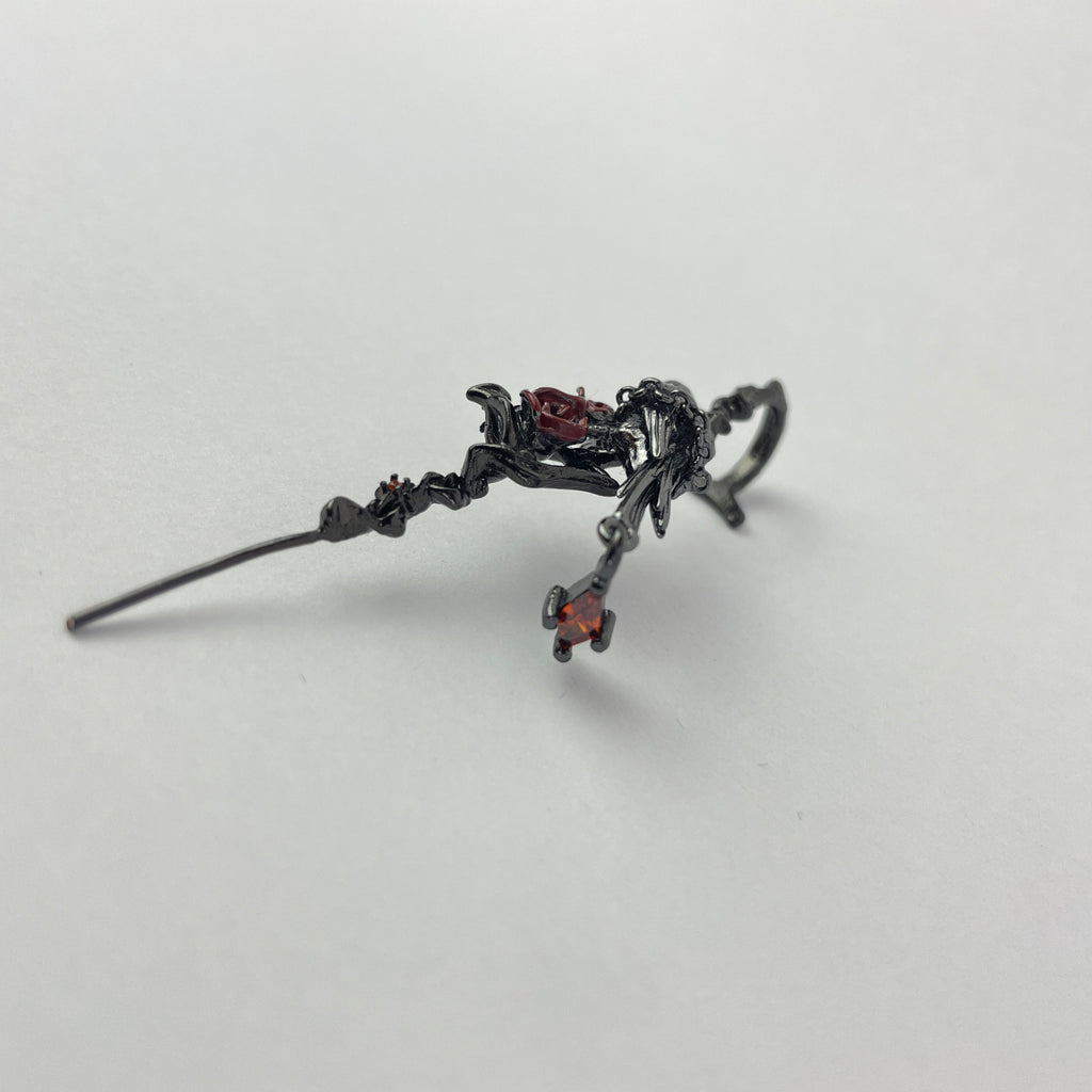 Black earring with decorative elements on a light gray background