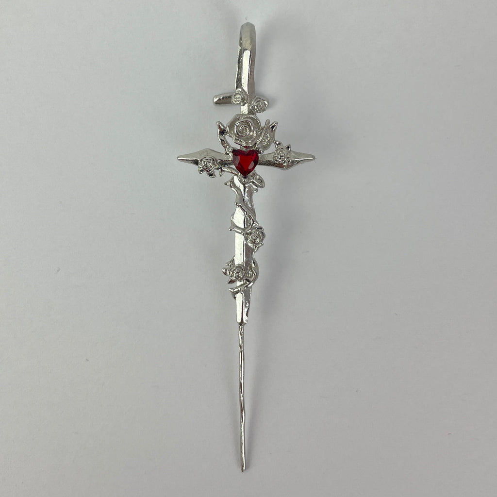 Silver hair clip with floral design and red gemstone on a gray background