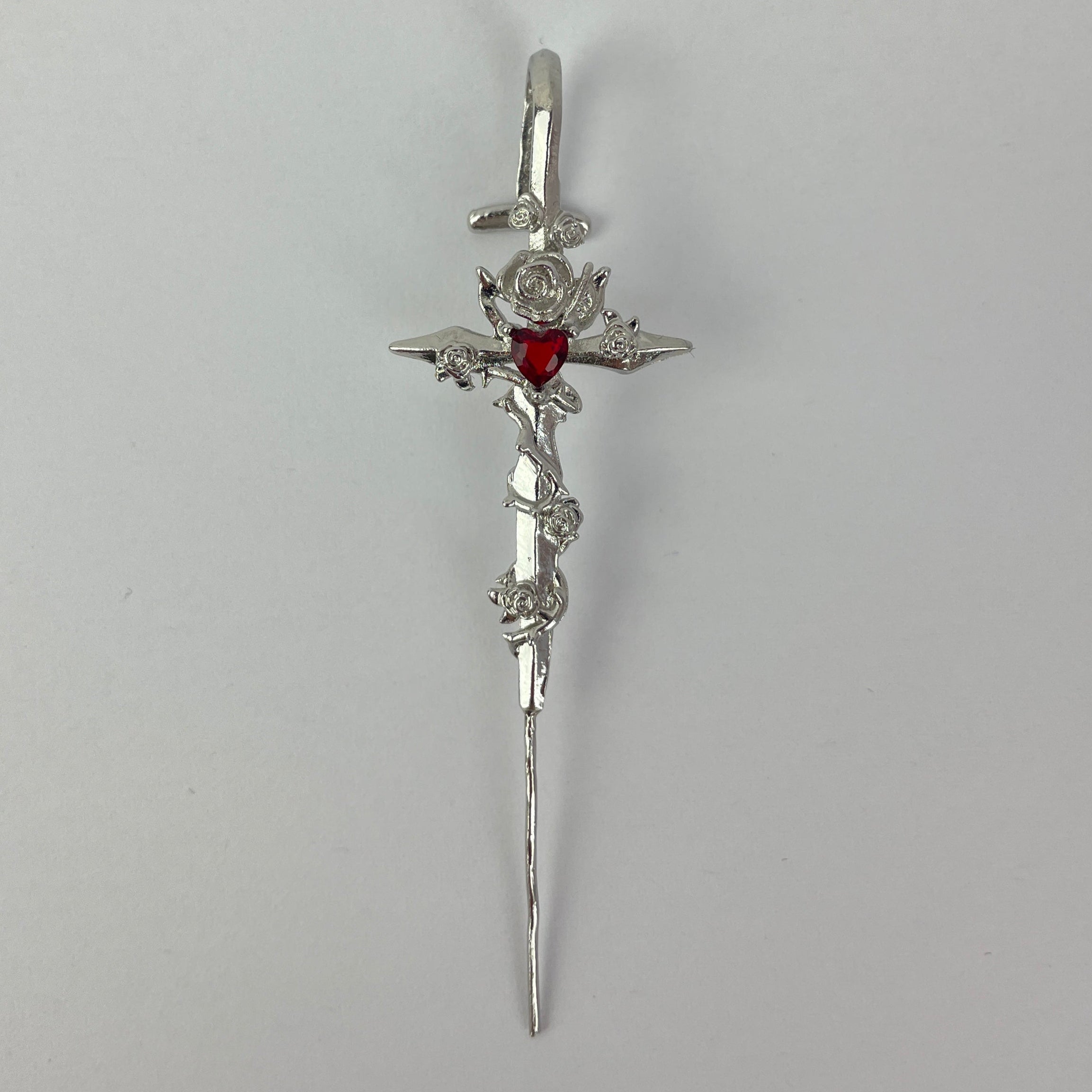 Silver hair clip with floral design and red gemstone on a gray background
