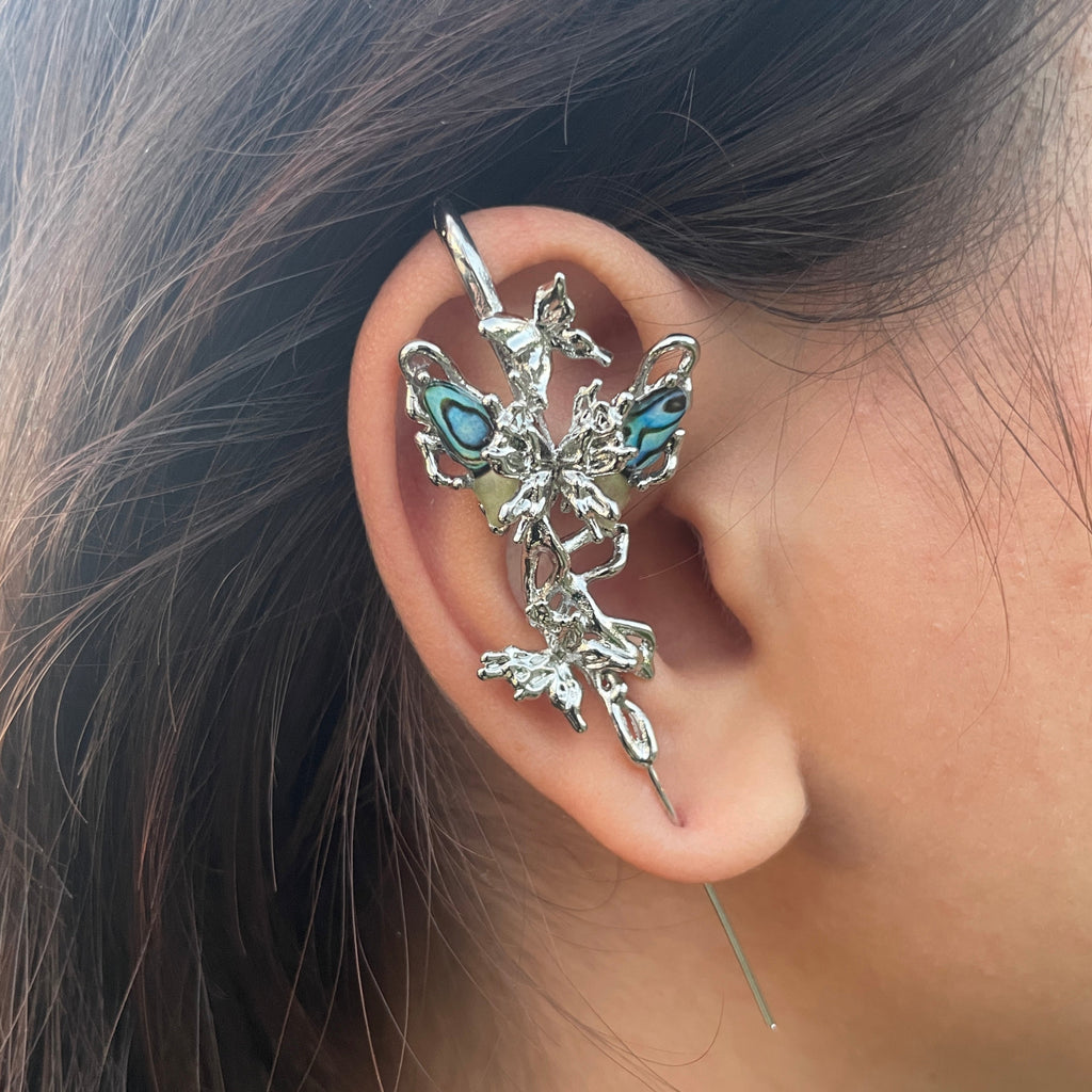 Close-up of an ear wearing a decorative silver and turquoise earring.