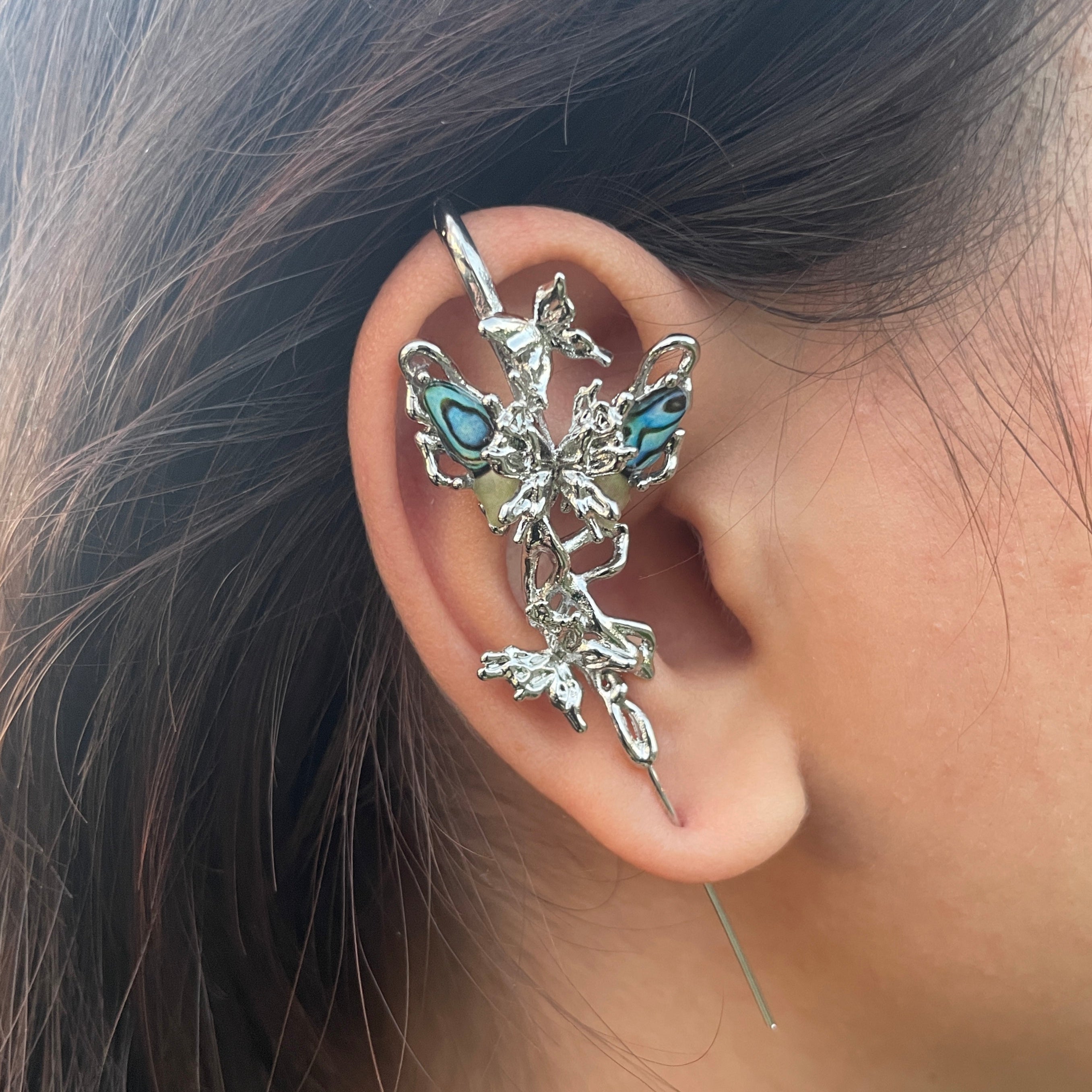Close-up of an ear wearing a decorative silver and turquoise earring.