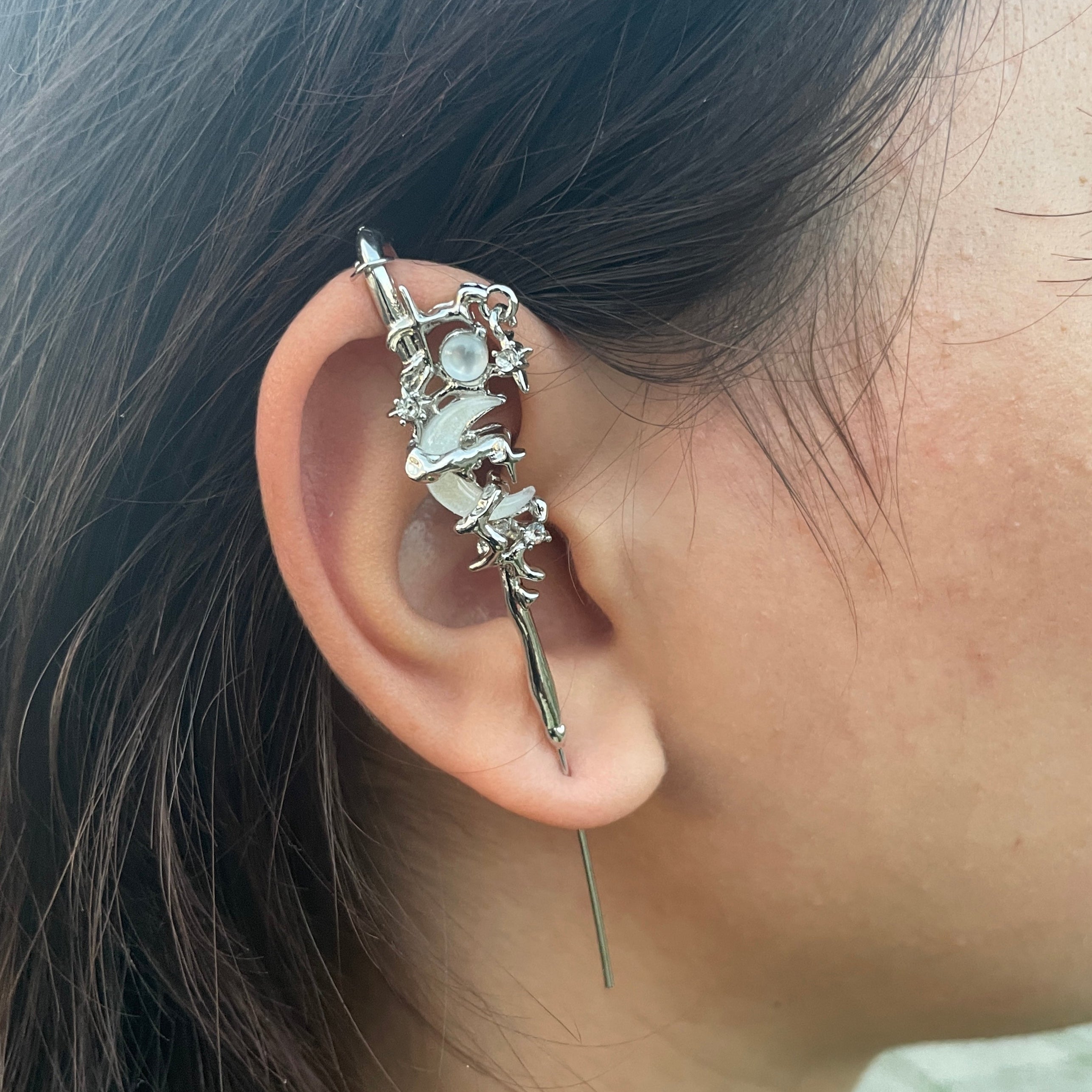 Close-up of an ear with a decorative silver earring against a blurred background