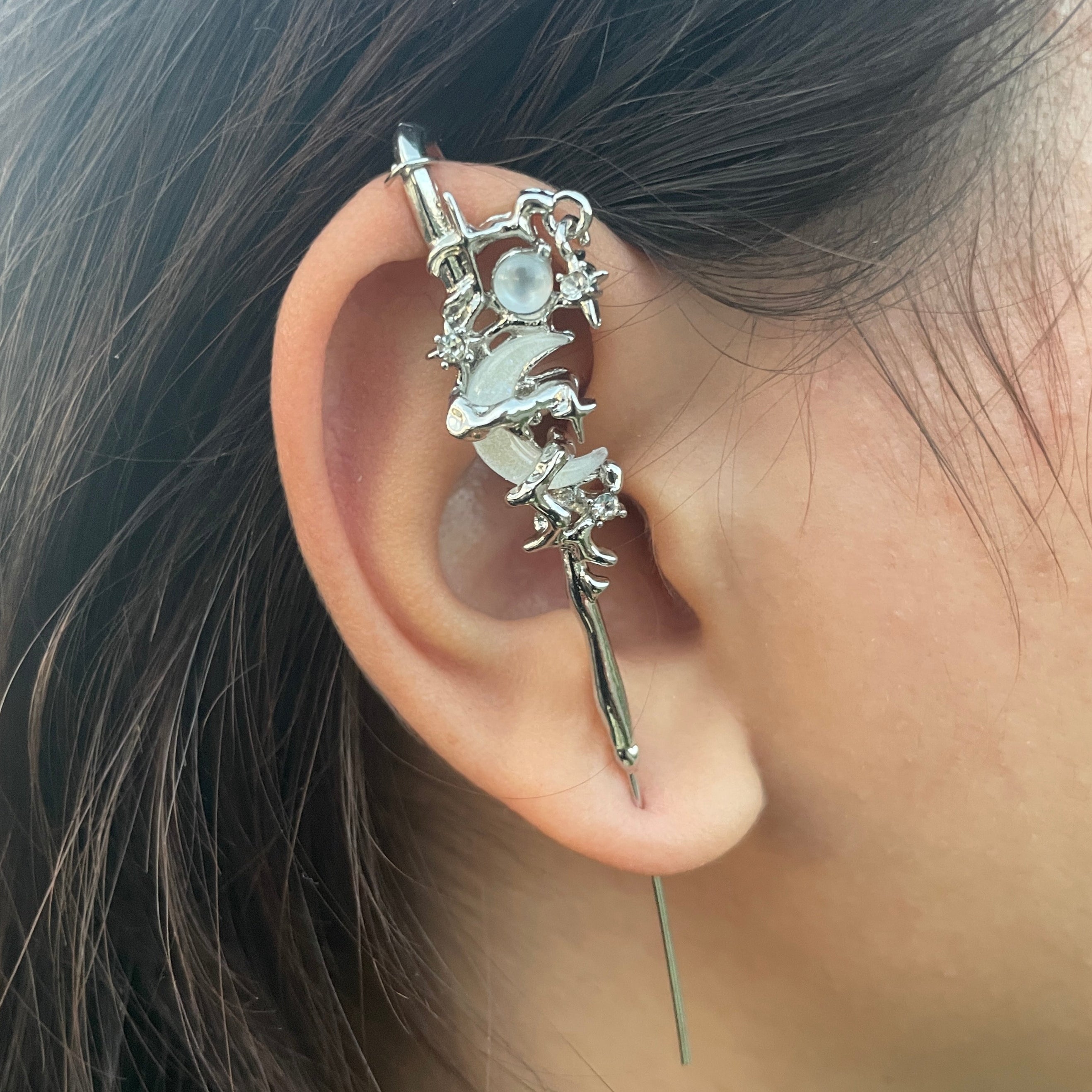 Close-up of an ear with a decorative earring, hair partially visible