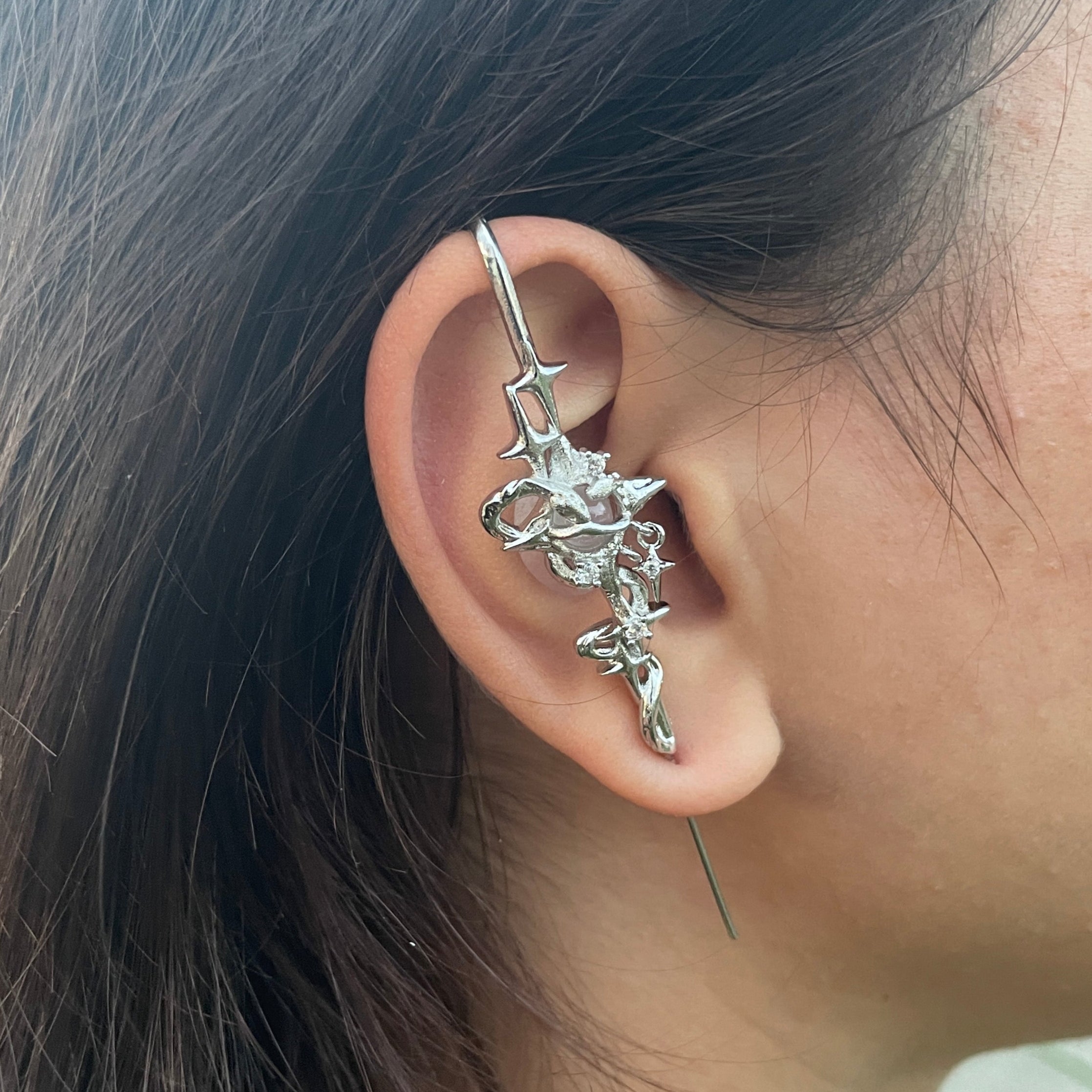 Close-up of an ear with a silver ear cuff featuring star designs.