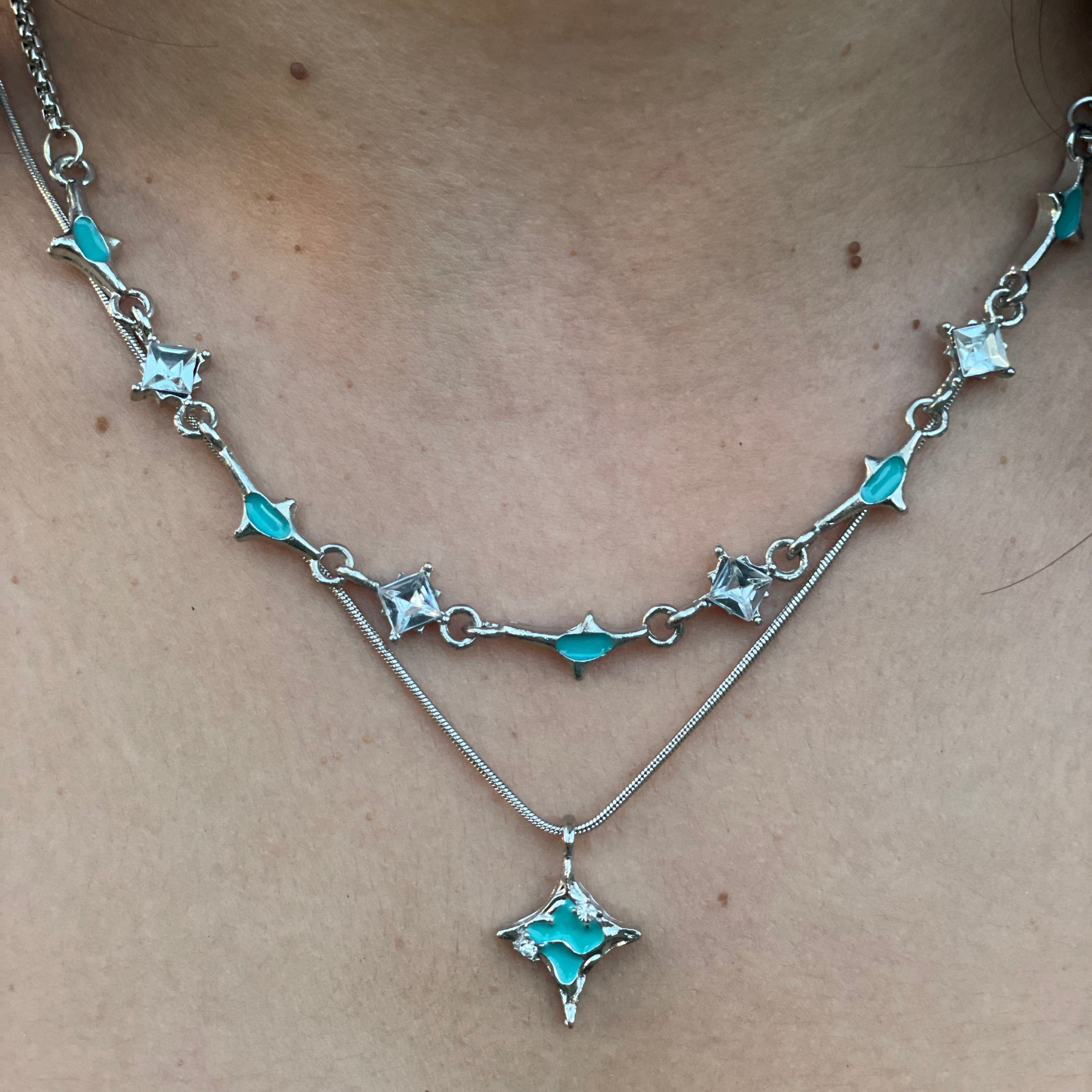 Necklace with star-shaped turquoise stones on a person's neck against a neutral background