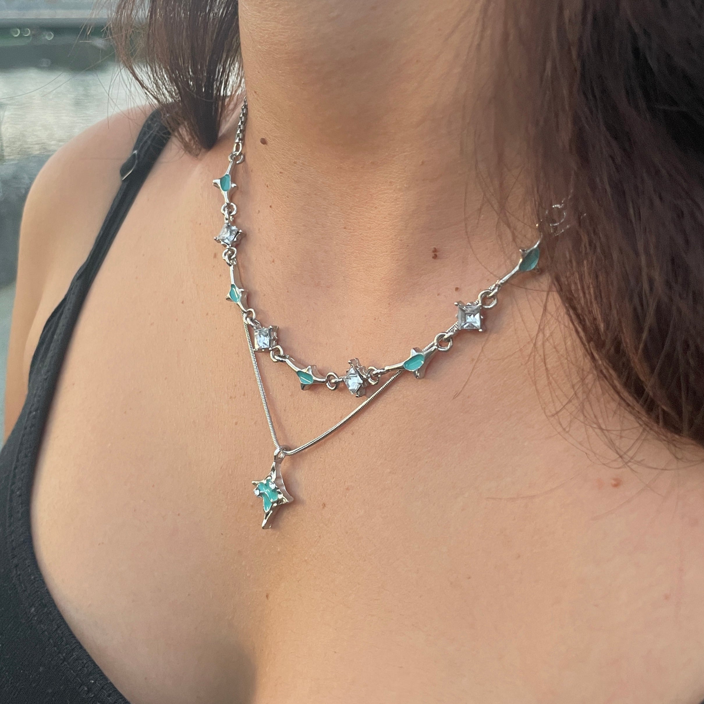 Close-up of a person wearing a delicate necklace with small stones.