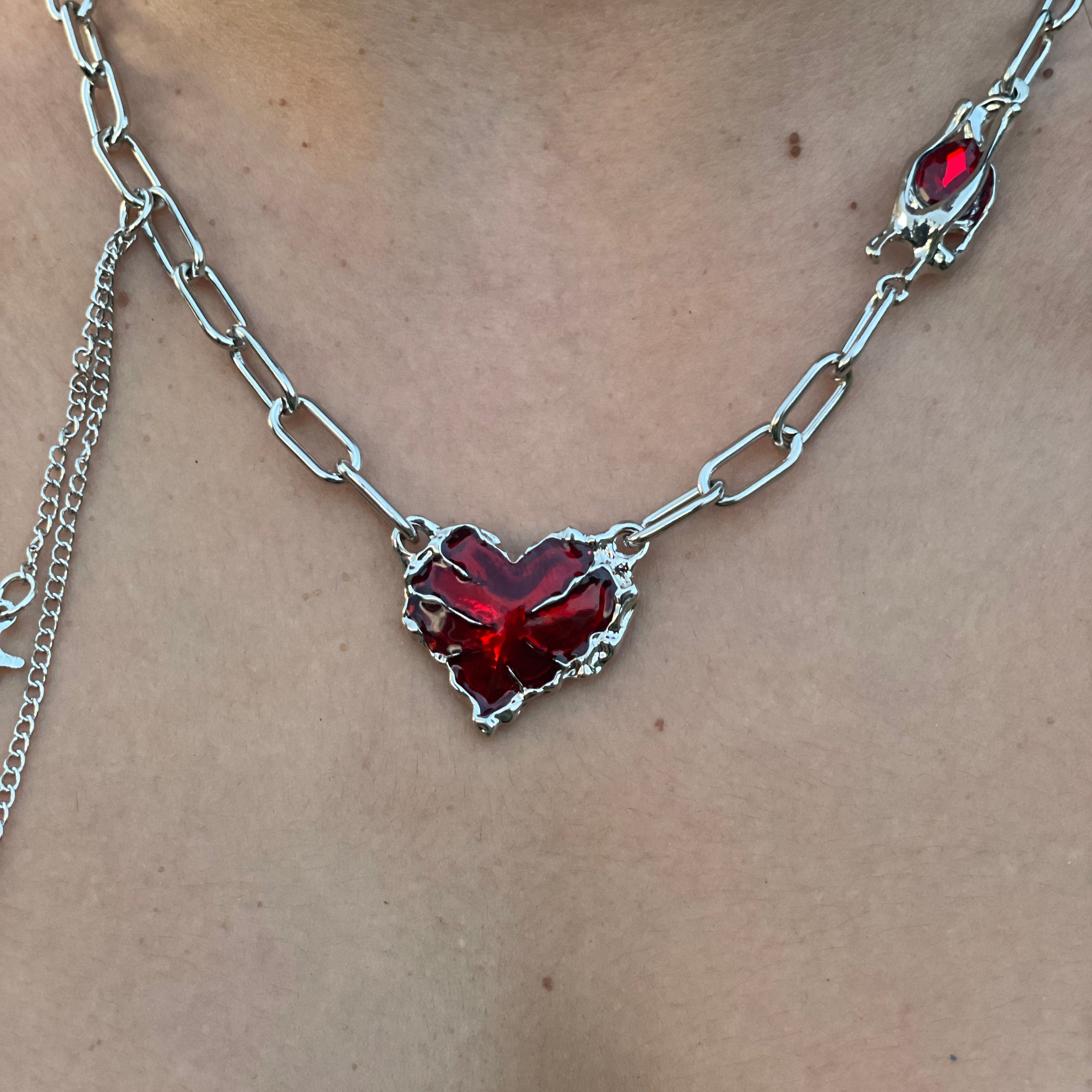 Necklace with a heart-shaped red gemstone on a plain background