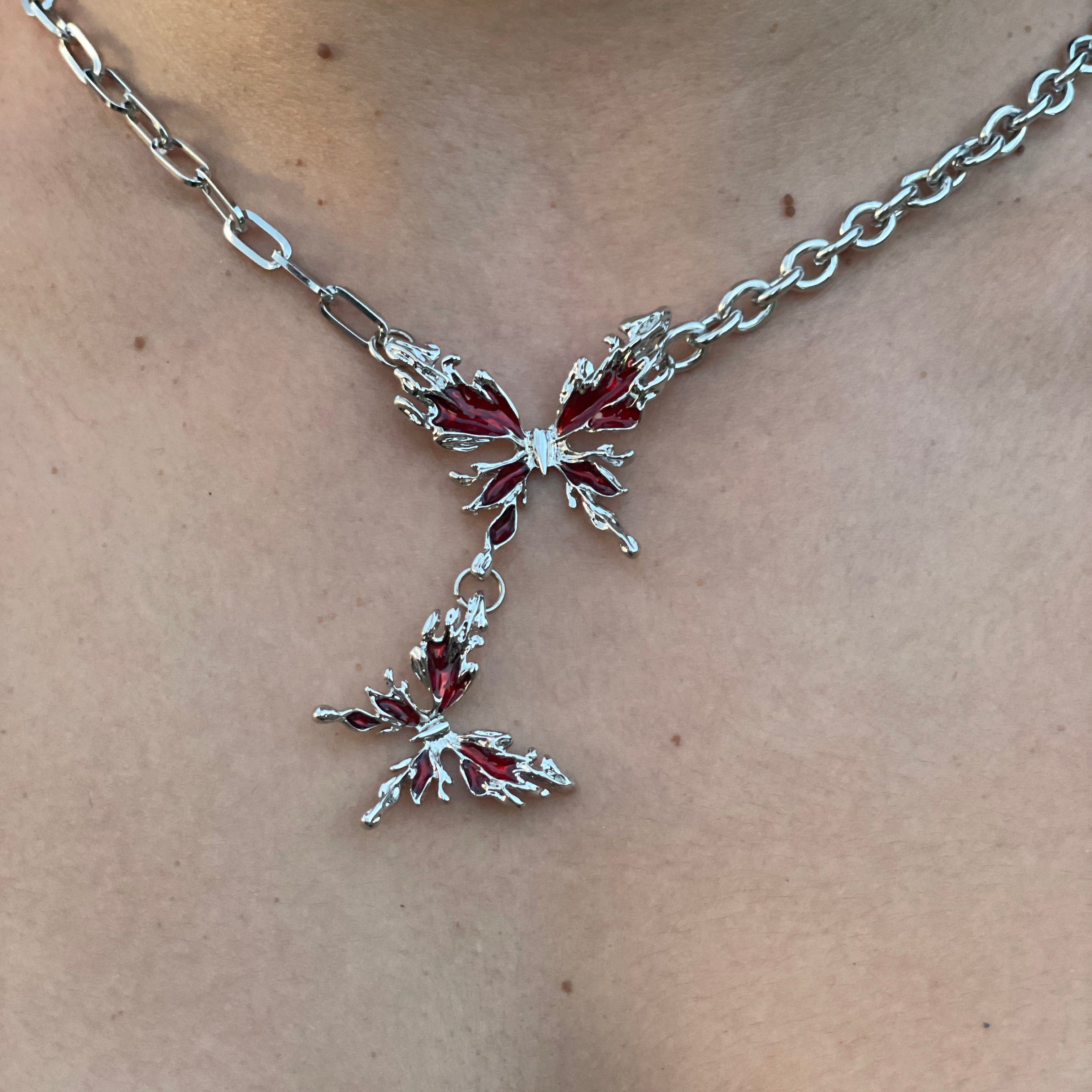 Silver butterfly body chain with red stones on a person's shoulder