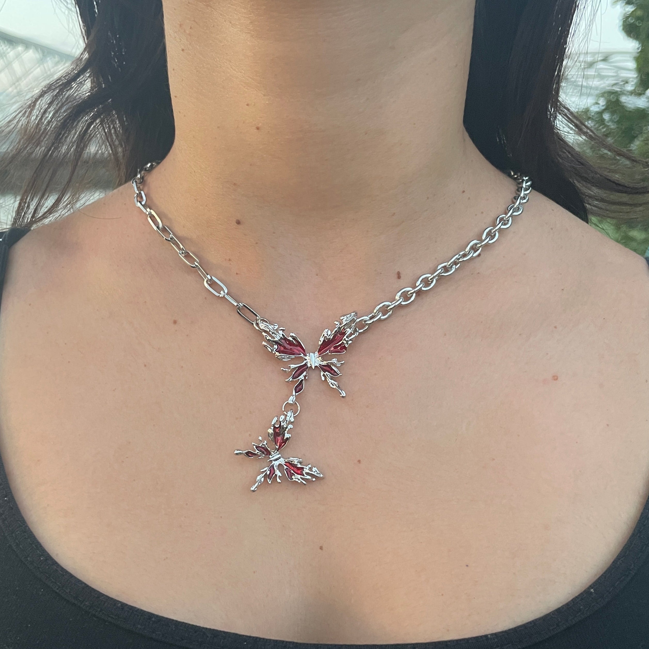 Person wearing a black top with a decorative chain accessory on their shoulder.