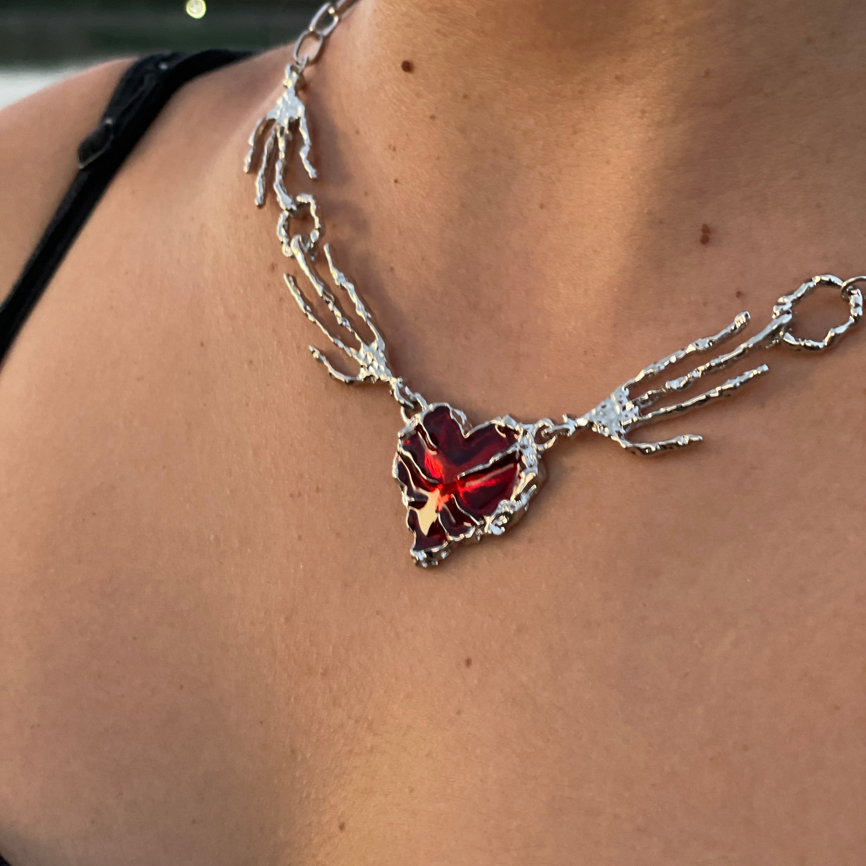 Necklace with a red flower pendant on a person's neck