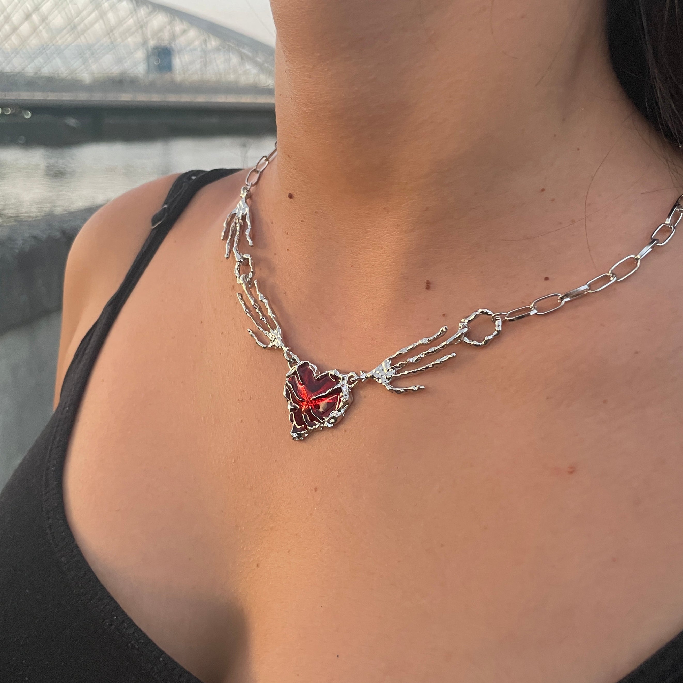 Close-up of a necklace with a red heart pendant on a blurred background