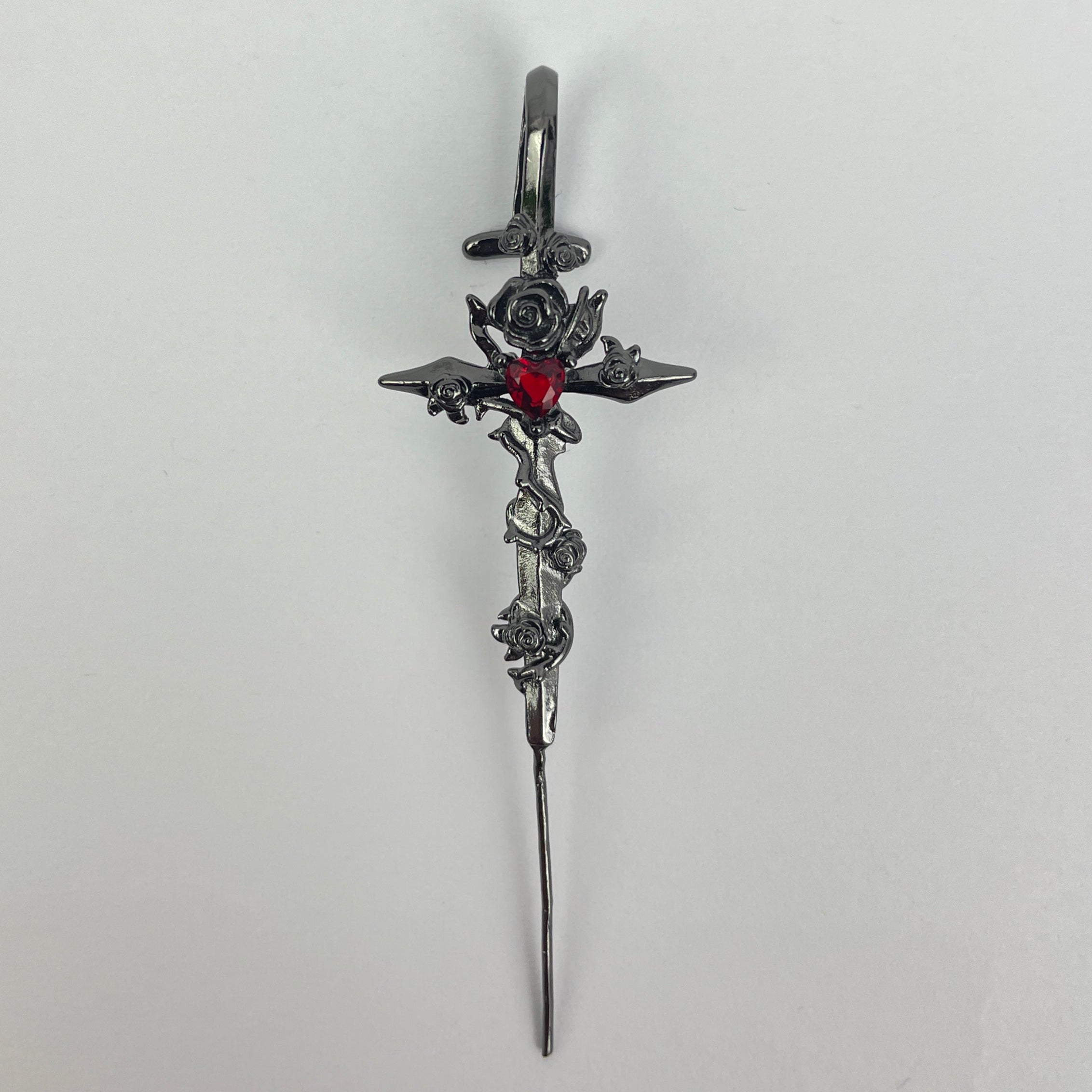 Decorative hairpin with floral design and red gemstone on a white background