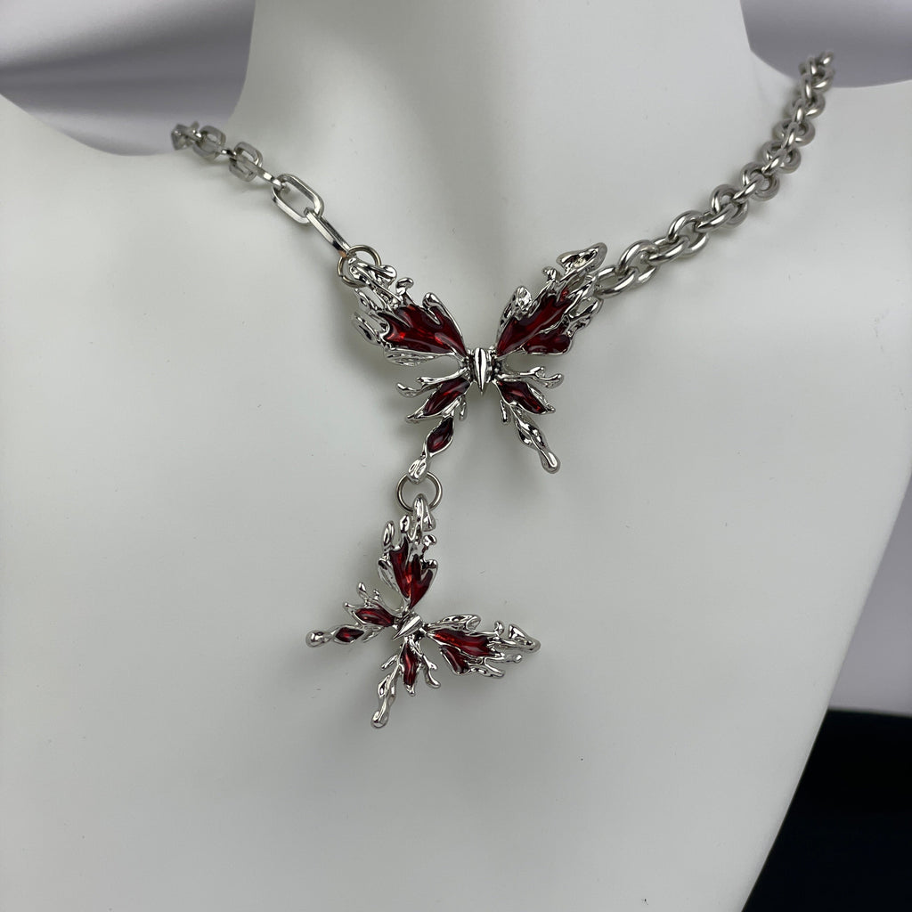 Butterfly-shaped necklace with red gemstones on a mannequin.