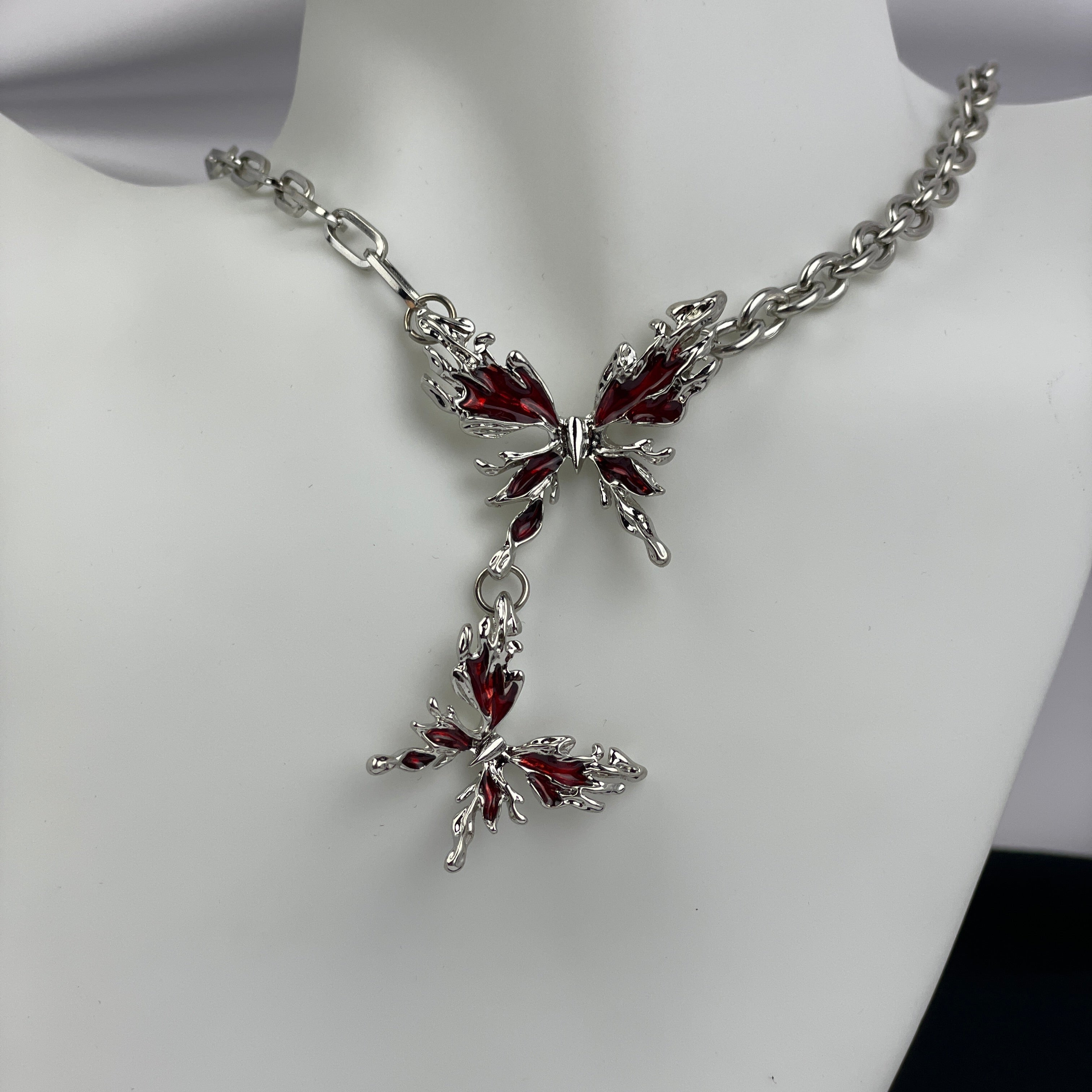 Butterfly-shaped necklace with red gemstones on a mannequin.